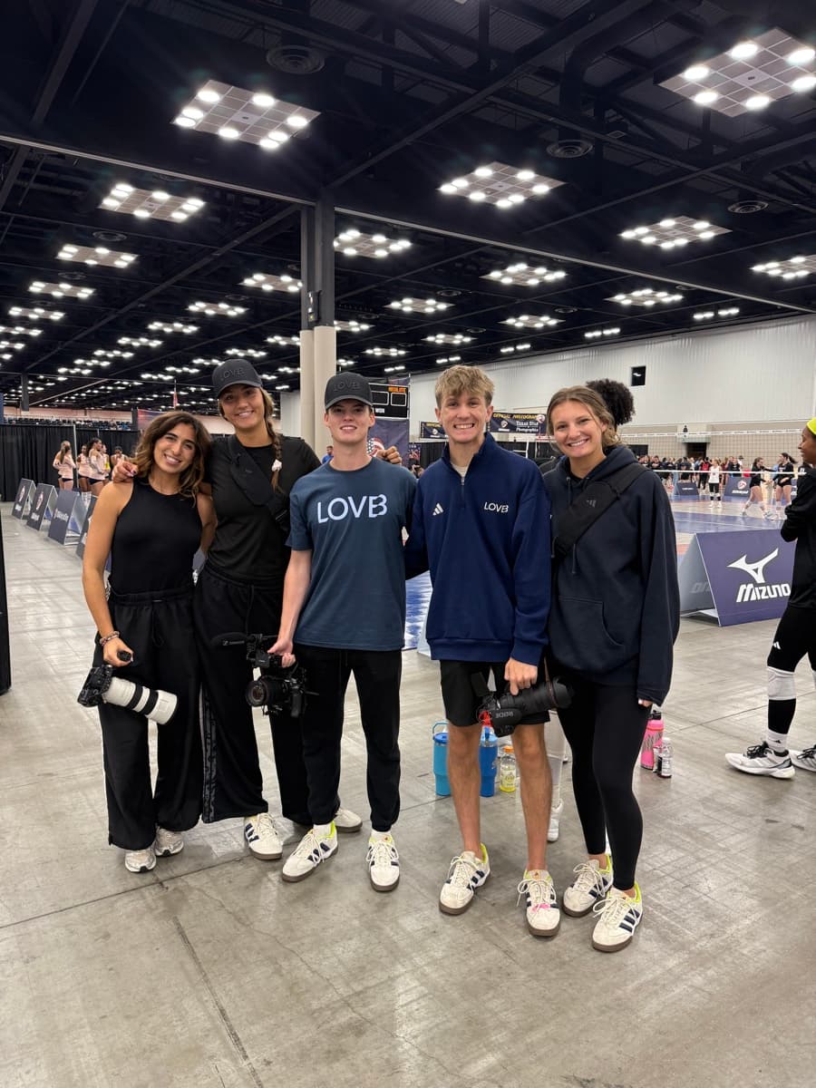 Makenna with the League One Volleyball media team, cameras in hand, courtside at an event