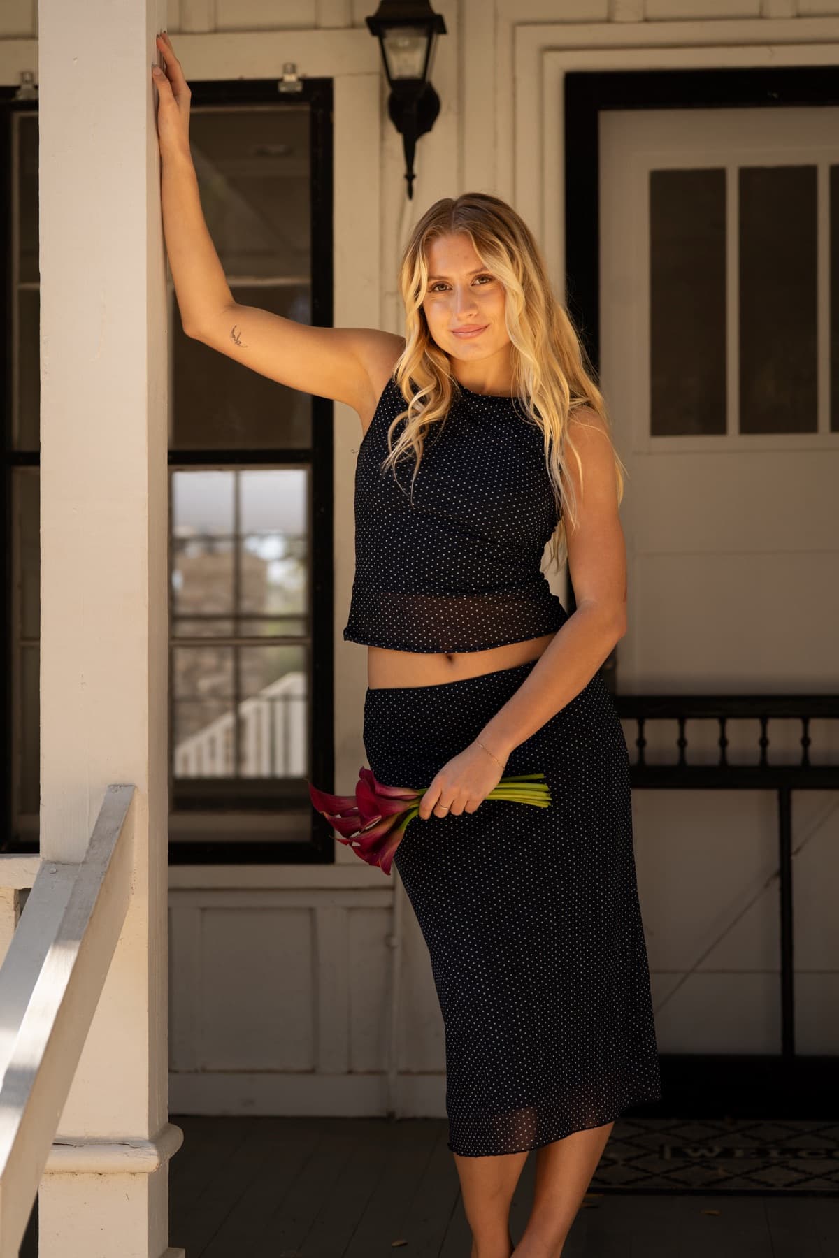 A portrait on a porch, holding a bouquet of flowers