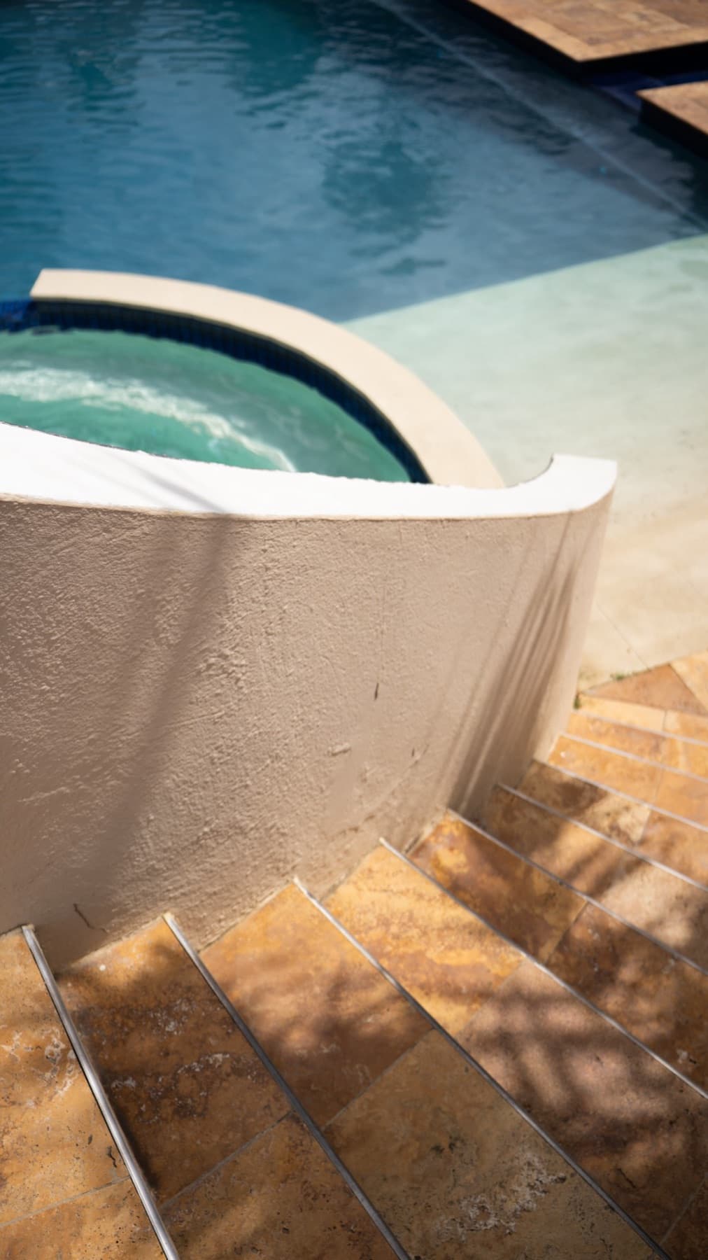 A curved pool wall and travertine steps beside the spa at Divi Dive Resort in Bonaire