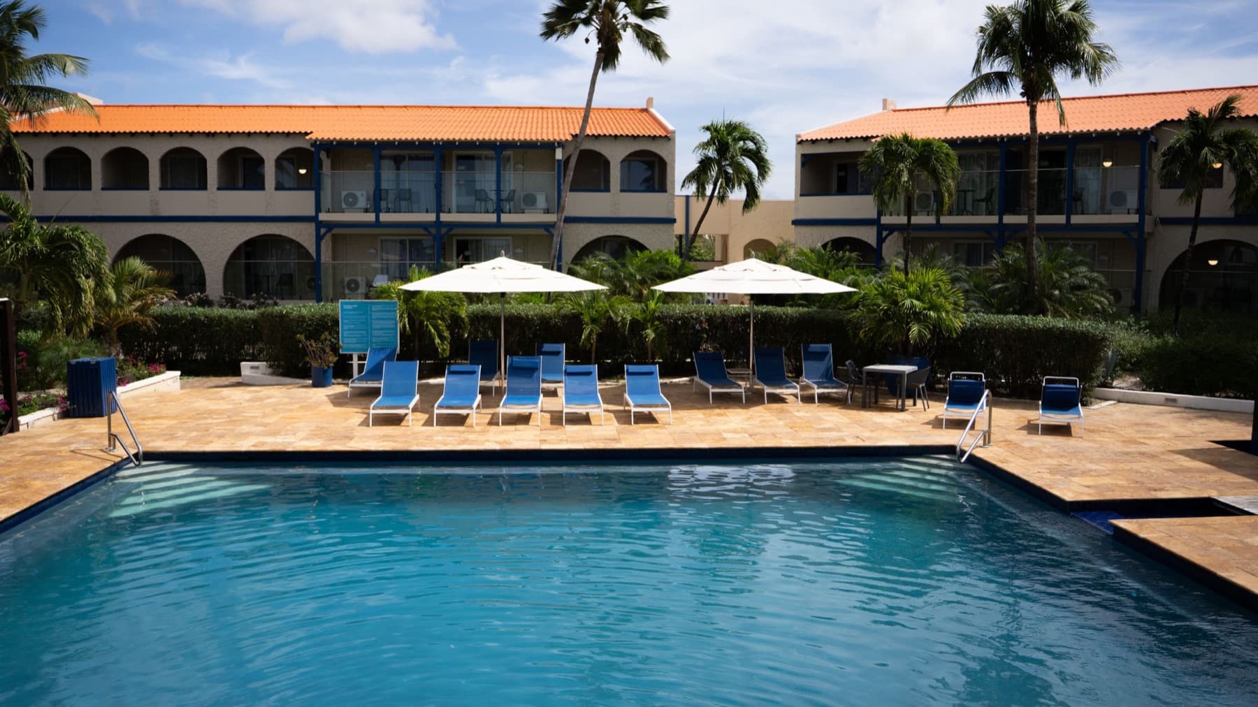 Wide view of the pool, blue loungers and rooms at Divi Dive Resort in Bonaire